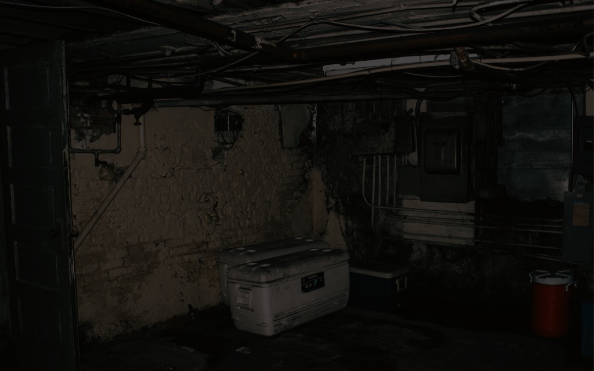 Dark basement corner with stained foundation walls and moisture history